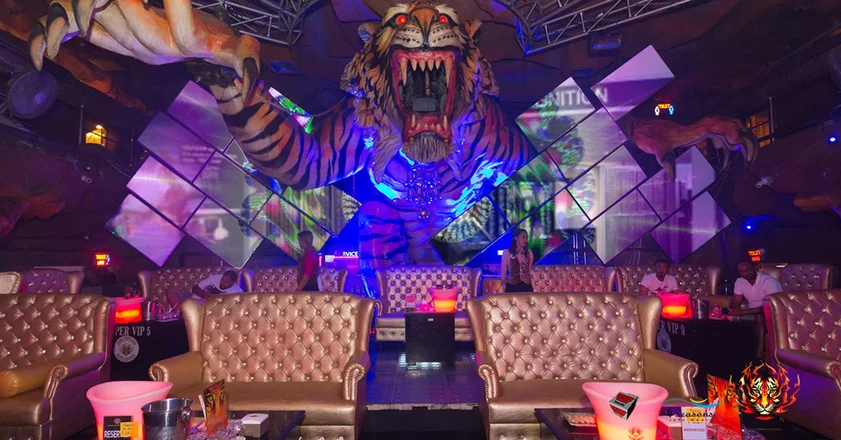 Artistico videowall mosiaco nella lounge del Tiger Night Club, con una grande tigre al centro delle pareti e un'area salotto di fronte
