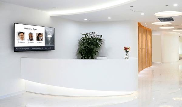 Banco d'ingresso della sala d'attesa, con dietro uno schermo con i tempi di attesa, le informazioni sul medico e l'eventuale presenza di un medico.
