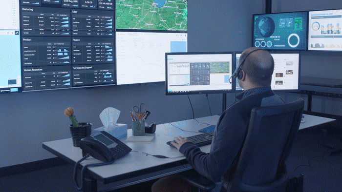 GIF di un dipendente della logistica che digita alla sua scrivania in ufficio davanti a un videowall, poi in remoto dalla sua scrivania di casa davanti a una finestra