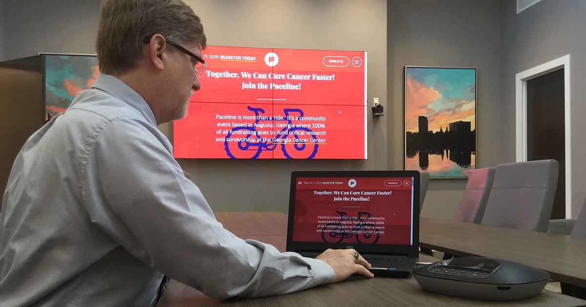 Sala riunioni del Medical College of Georgia, con un uomo che utilizza il suo laptop e Userful per visualizzare una pagina web su una parete video alle sue spalle.