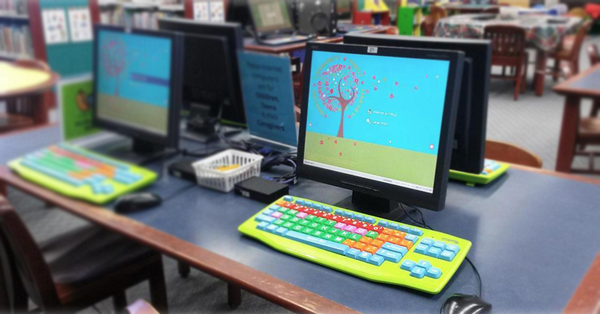 Un tavolo nella biblioteca pubblica della Comunità di Varsavia con computer che usano Userful Desktop e tastiere colorate