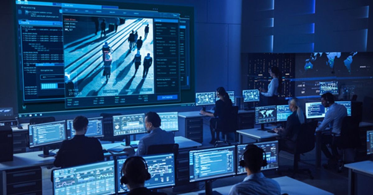 Security operations center with employees working at workstations and a video wall displaying visual recognition in live footage