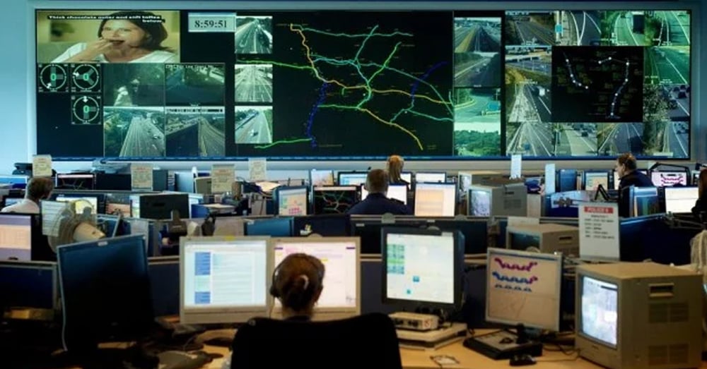Centro operativo per le emergenze, con pareti video che visualizzano le telecamere e i percorsi del traffico in tempo reale e dipendenti che lavorano alle postazioni di lavoro.