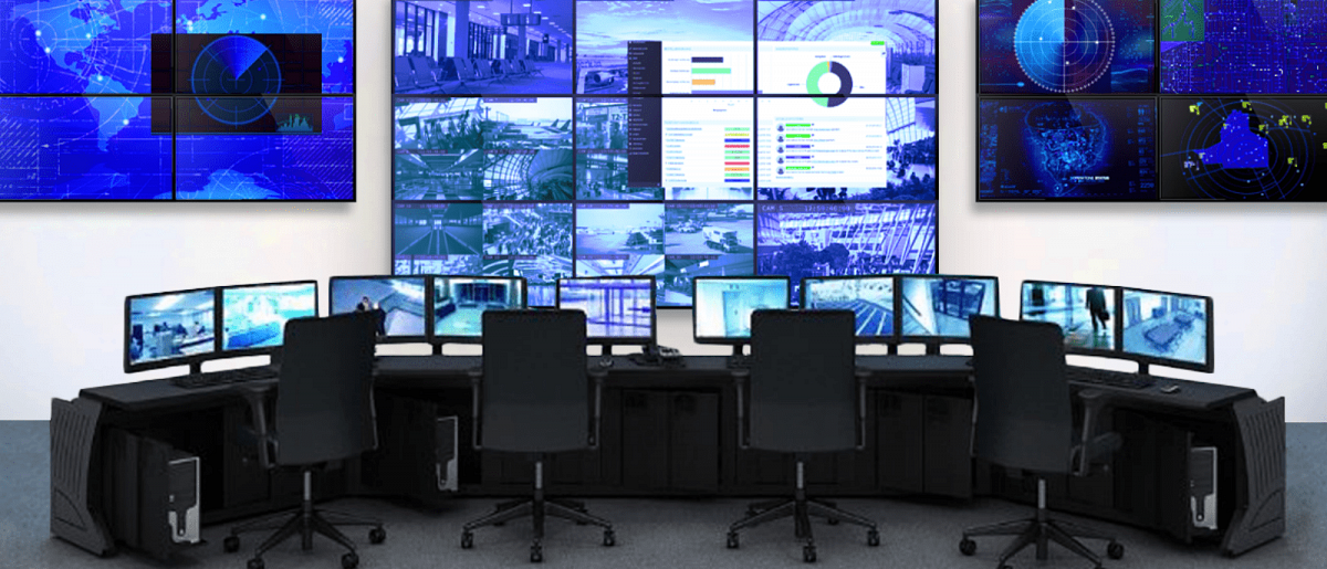 Sala di controllo vuota con 4 postazioni di lavoro e 3 videowall che visualizzano le riprese in diretta delle telecamere di sicurezza e i cruscotti di dati.