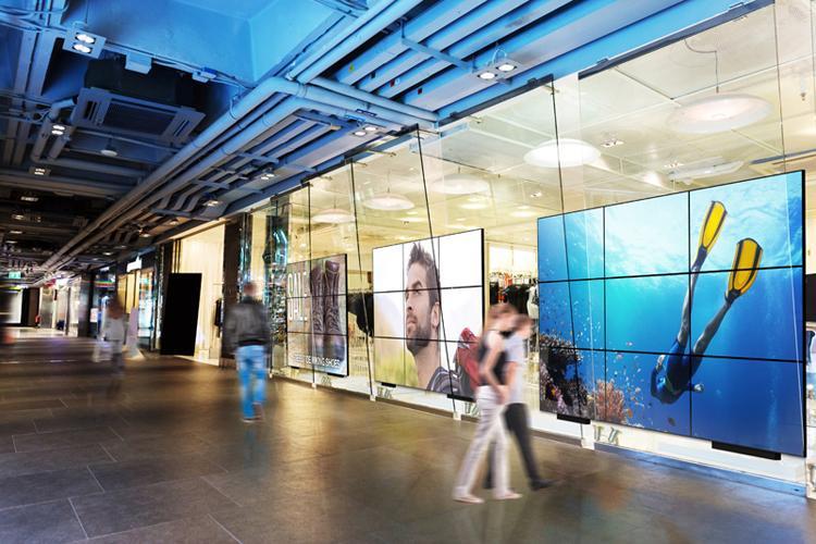 Più videowall Userful di grandi dimensioni nel corridoio di un centro commerciale, per visualizzare pubblicità e opere d'arte.