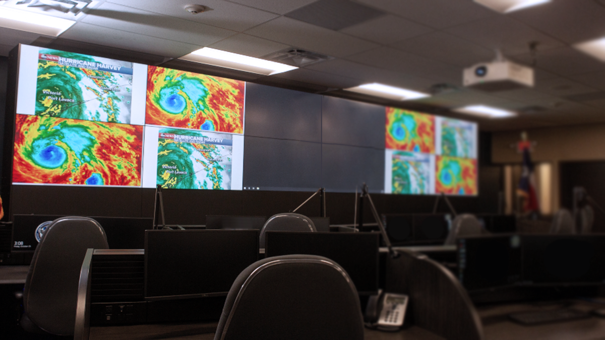 Empty control room with weather radars displayed on a large video wall, and workstations