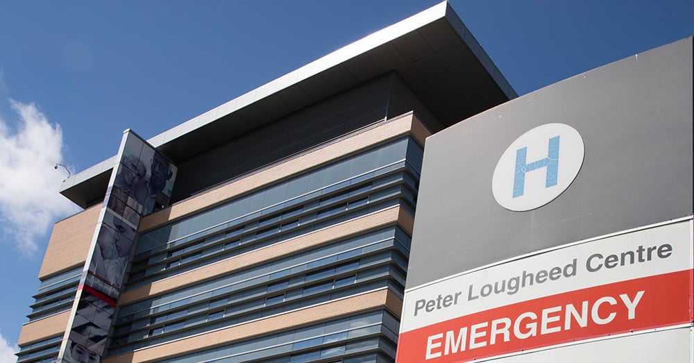 Una foto del cartello di emergenza del Peter Lougheed Center Hospital e dell'edificio dell'ospedale contro un cielo azzurro