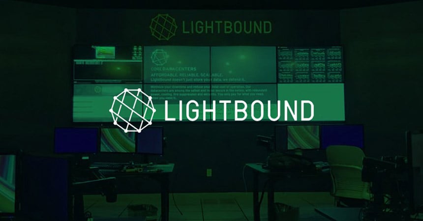 Sala di controllo Lightbound vuota con 2 postazioni di lavoro e videowall che visualizza siti web, dati e pubblicità con sovrapposizione verde e logo