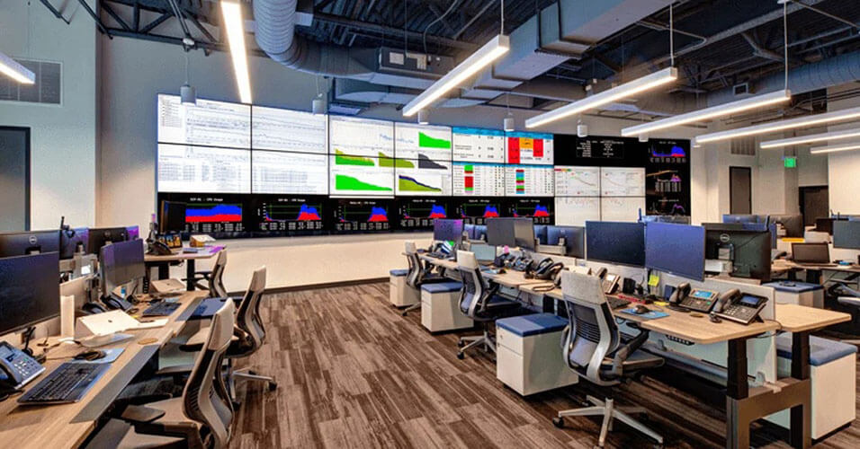 Centro operativo di rete SpectrumVoIP vuoto con molte postazioni di lavoro e una parete video più grande che visualizza i cruscotti dei dati.